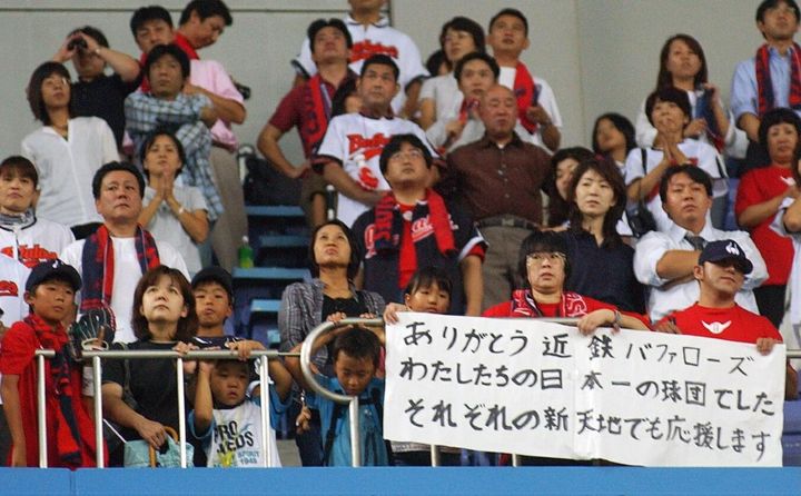 近鉄の本拠地最終戦でメッセージを掲げて立ち尽くすファン（2004年9月、時事）
