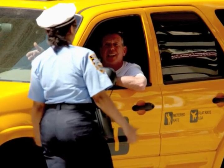 路上駐車中のタクシードライバーに対して、移動するよう伝える女性警察官