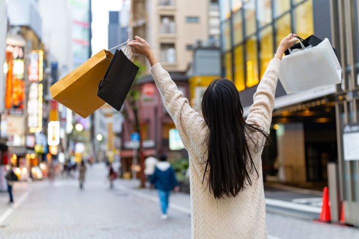 複数のショッパーを手にごきげんで渋谷の街を歩く女性