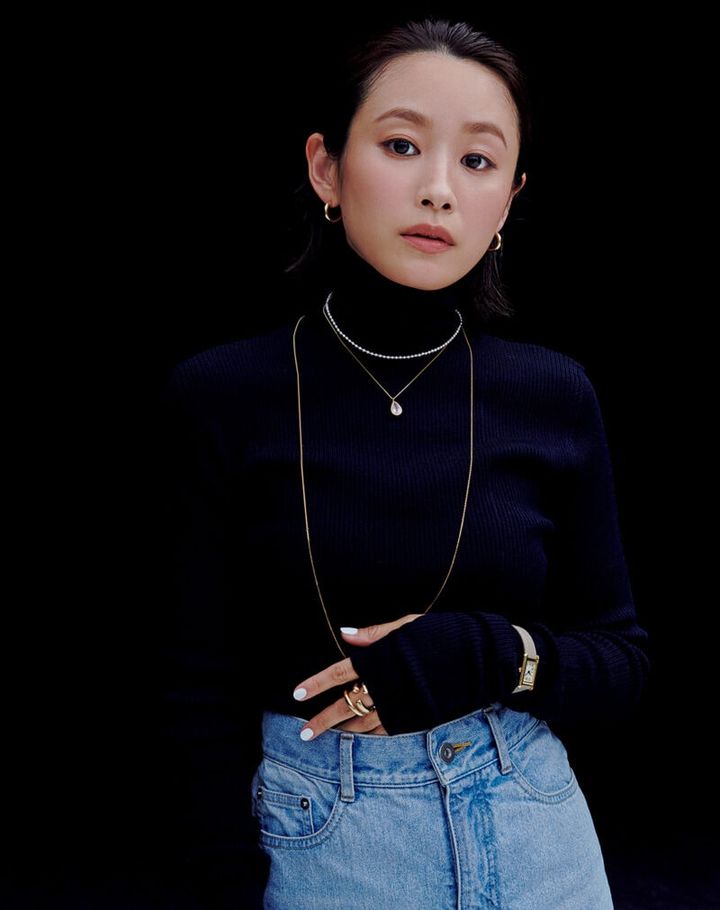 高橋愛 時計￥24,200（シュールメジュール／ヒロブ ルミネ池袋店） ピアス［K24 ゴールドプレーテッド シルバー］￥24,200、リング［K24 ゴールドプレーテッドシルバー］￥48,400（ともにブランイリス／ブランイリス トーキョー）ロングネックレス［K18YG］¥121,000、パールネックレス［K18YG 淡水パール］￥165,000、カラーストーンネックレス［K18YG、ローズクォーツ］￥132,000（すべてマリハ） ネイビータートルニット¥20,900、デニムスカート￥28,600（ともにルシェルブルー）