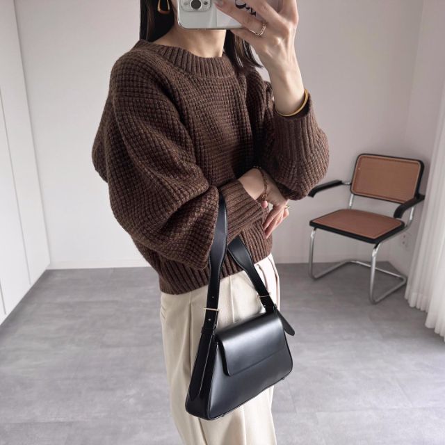 ブラウンのメランジセーターを着用