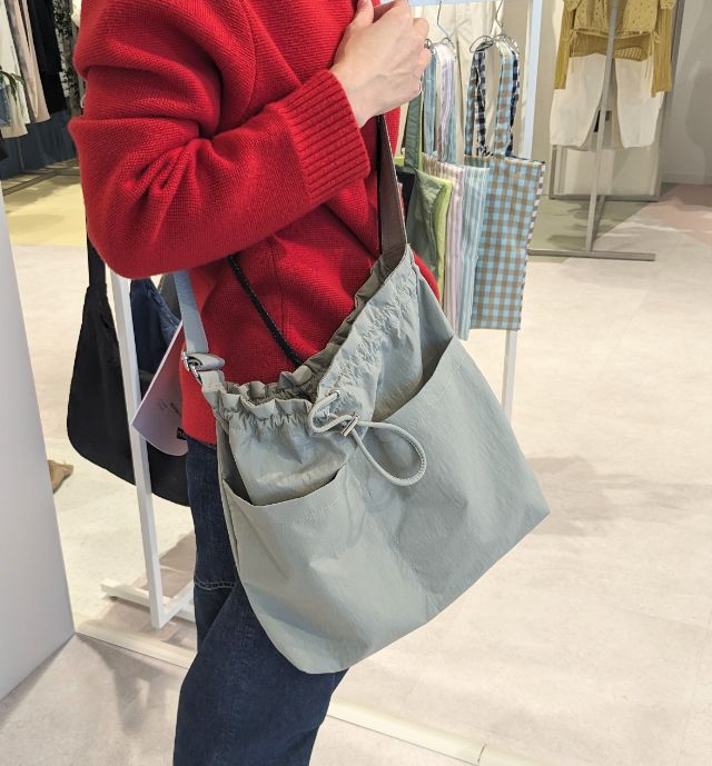 カーキのナイロンドローストリングショルダーバッグを着用