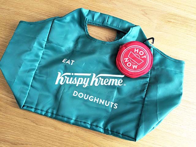 「クリスピー・クリーム・ドーナツ 福袋 2024」アイテム「オリジナルエコバッグ2024」と「HOT LIGHTポーチ」がテーブルに広げられている光景
