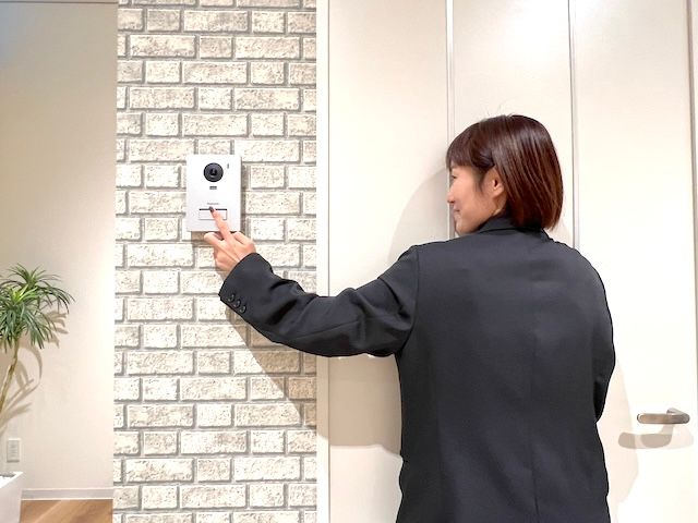 ドアホンを押す女性