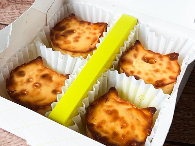 こんがりと焦げ目がついた手のひらサイズのねこ型のチーズケーキが4つ