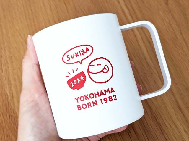 「すき家オリジナルマグ」を手で持っている様子。