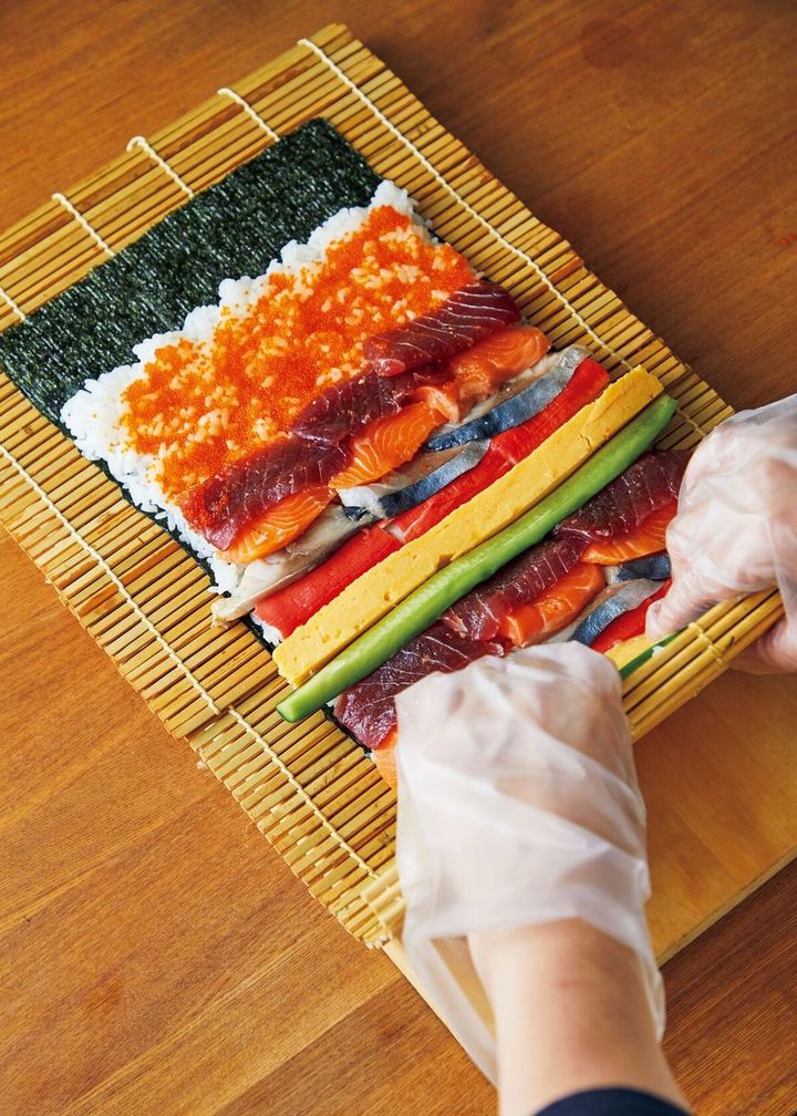 手前の巻きすを持ち上げて一周したら、左手で太巻きをぎゅっと押さえ、形を整えて。