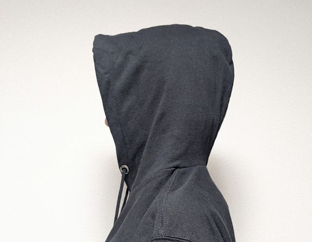 黒のパーカーのフードをかぶっている