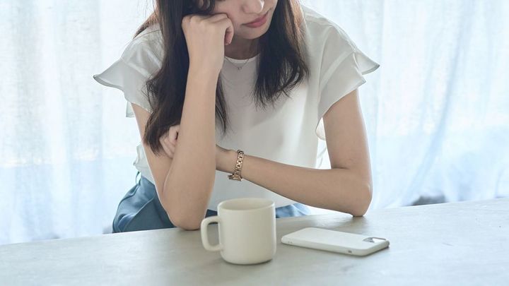 肘をついて考える女性