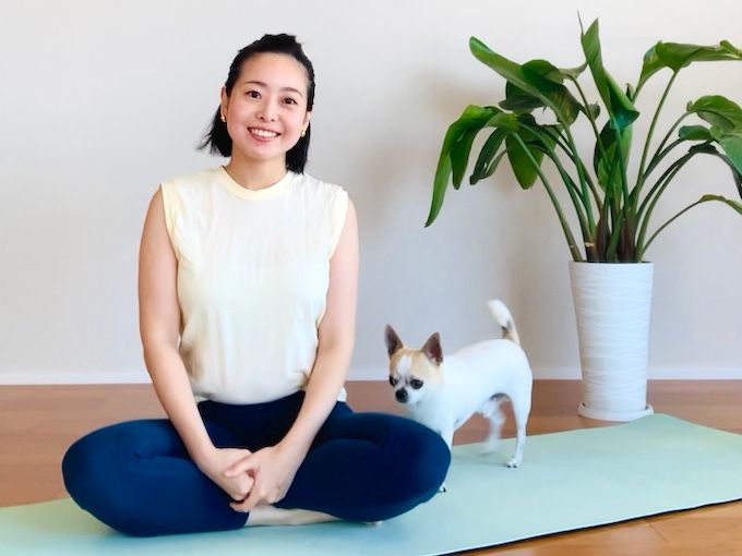あぐら姿勢でマットの上に座る伊藤さんとワンちゃん