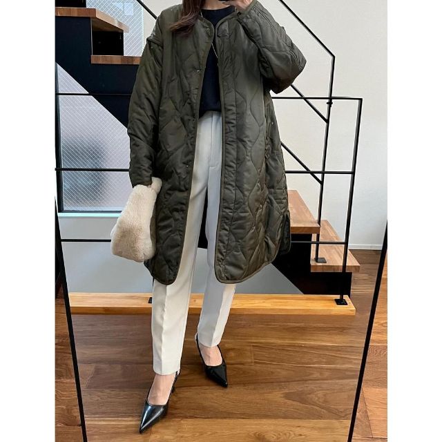 カーキのキルティングコートと黒のニットトップスの全身コーデ