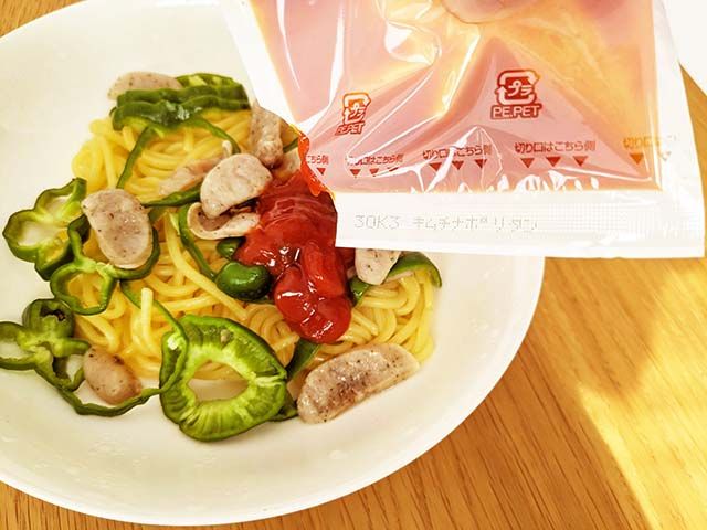 耐熱皿に入れられ加熱された「キムチナポリタン」の麺がに液体ソースがかけられている様子