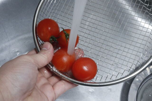 ダイソーのステンレス浅ザル（油切 皿19cm）にトマトを入れて洗浄する様子