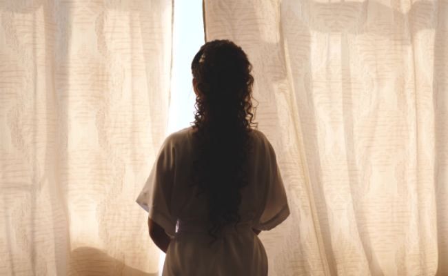 カーテンの隙間を見る女性のイメージ