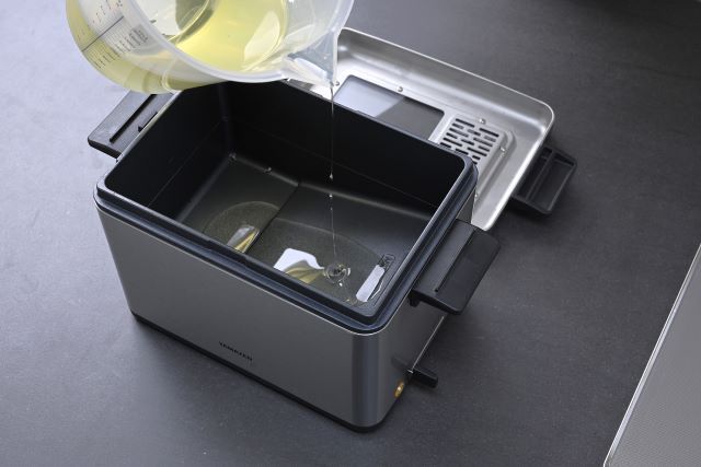 フライヤーに油を注いでいる