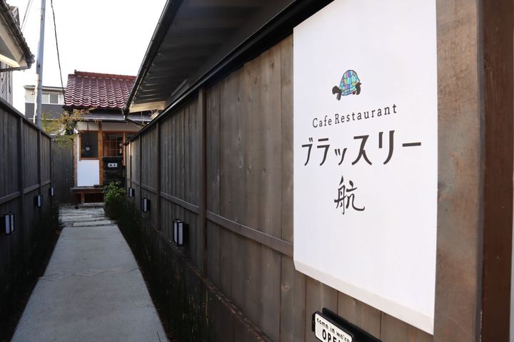 塀に囲まれた細い道の先にある