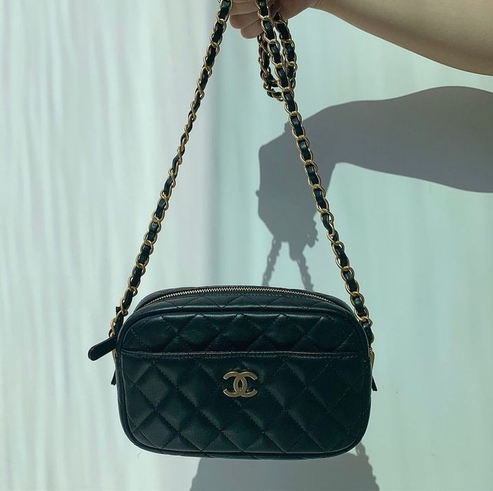 黒いシャネルのチェーンバッグを持つ人の手