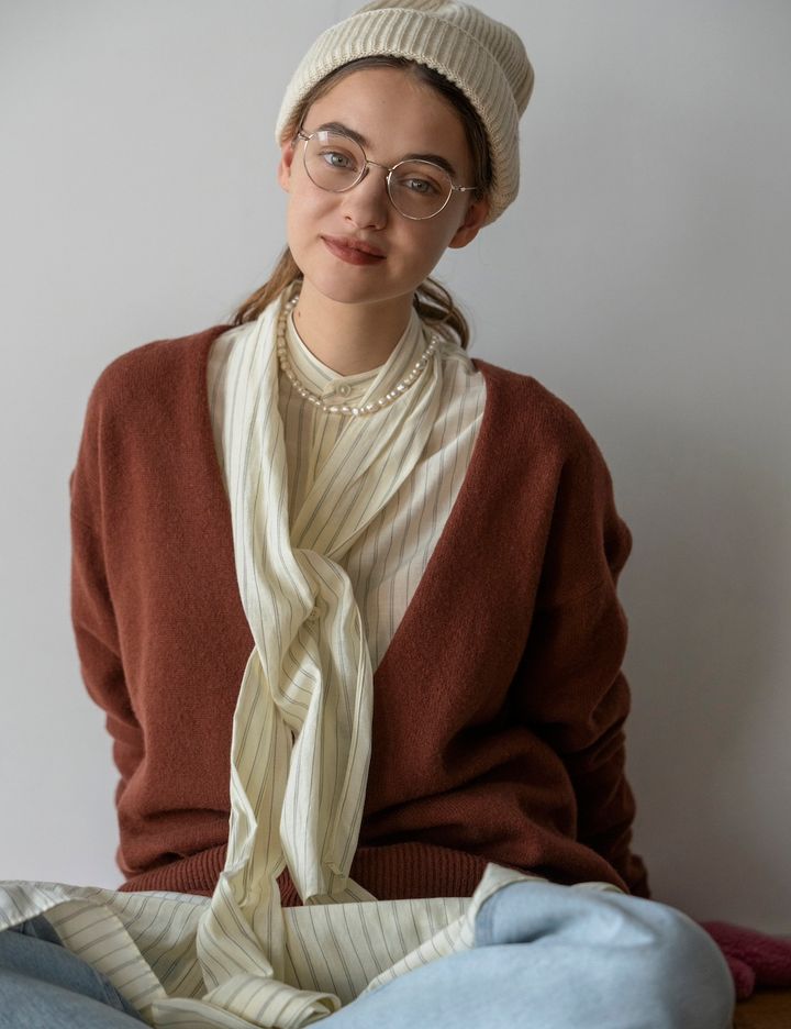 シャーベットカラーのデニムには、レンガ色のVネックニットで色の対比を楽しむ。