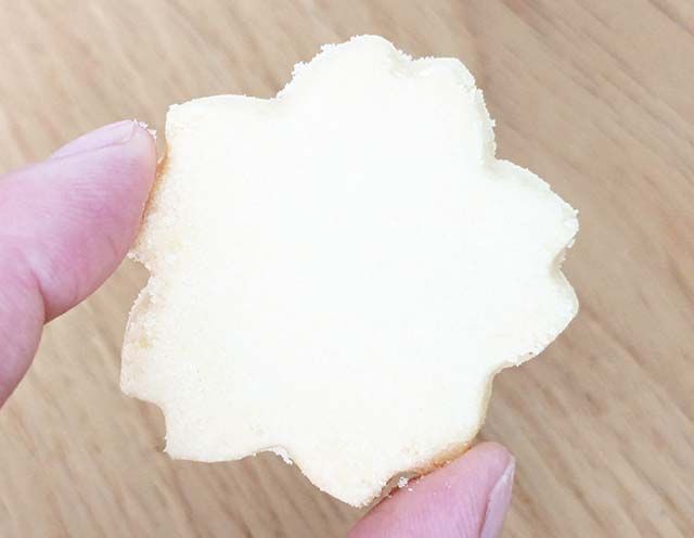 紀伊國屋「カラーミニスイーツバッグ（さくら）」の「桜型の塩クッキー」を指で摘んでいる様子