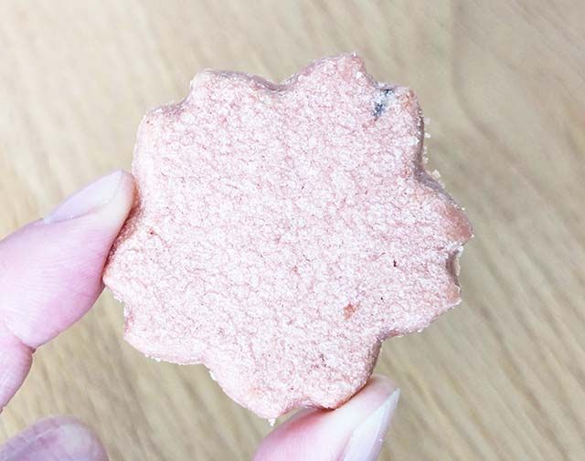 紀伊國屋「カラーミニスイーツバッグ（さくら）」の「春限定桜風味のクッキー」を指で摘んでいる様子