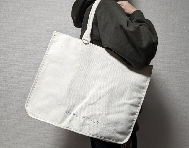 アイボリーカラートートバッグを持った