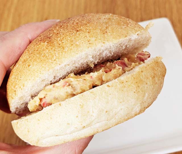 カルディ新商品「ザクザクいちごミルフィーユ」を丸いソフトフランスパンでサンドし手で持った様子