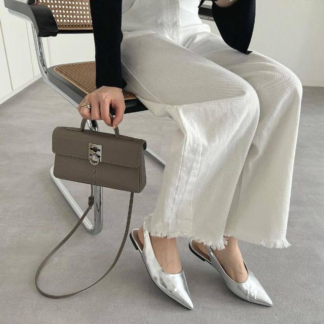 メタリックシルバーのバックストラップシューズを履いている