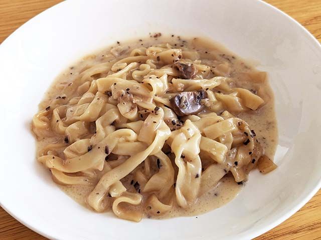 カルディ新商品「トリュフクリームの生フェットチーネ レンジアップ」が開封され、お皿に盛られた様子