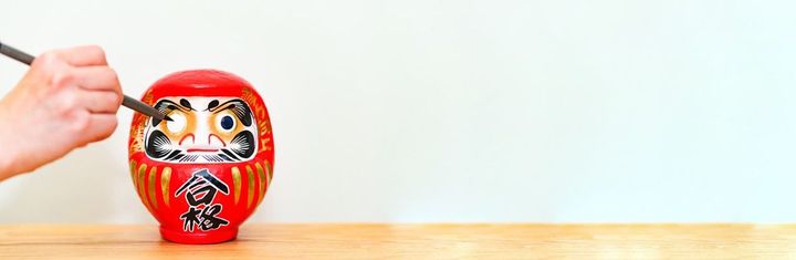 入試の勝利を願ってだるまの左目に墨を入れる