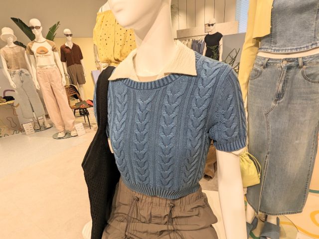 ブルーのケーブルクルーネックセーターを着用