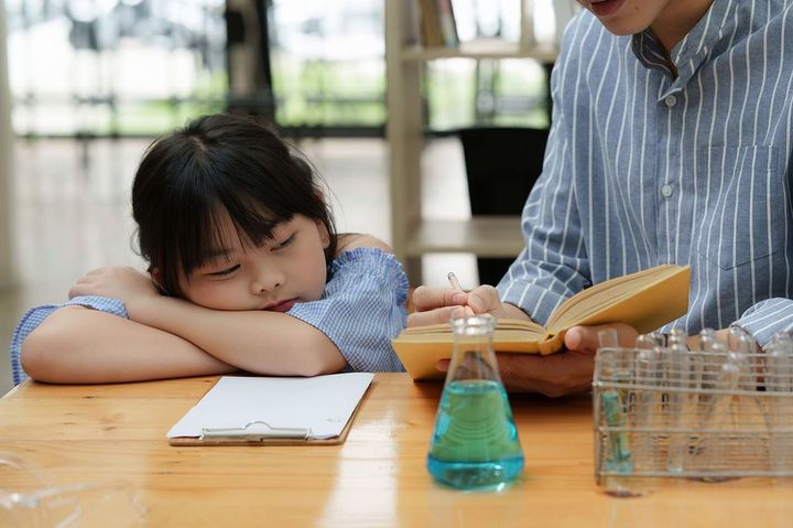 科学の実験をしながら眠そうにしている子ども