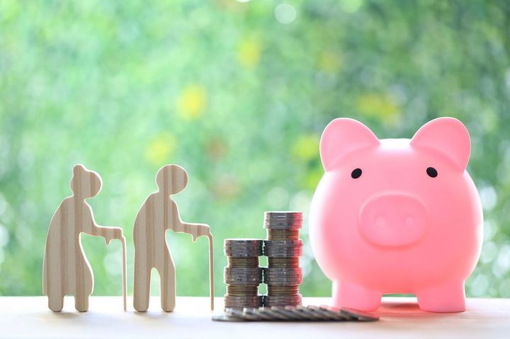 豚の貯金箱とシニアカップルのシルエット