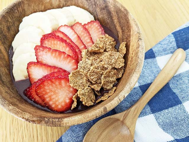 木製のボウルに入れられ、バナナ・いちご・オールブラン ブランフレークがトッピングされた「フルッタフルッタ お家でアサイーボウル」