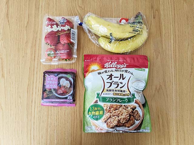 アサイーボウルの材料。「フルッタフルッタ お家でアサイーボウル」一袋・バナナ・いちご・オールブラン ブランフレークがテーブルに並べられている様子