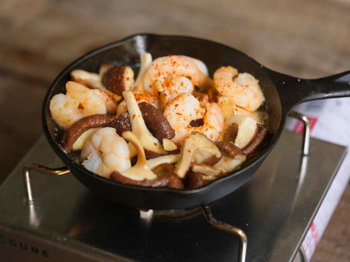 「春シイタケとエビのアヒージョ」に唐辛子を加える様子