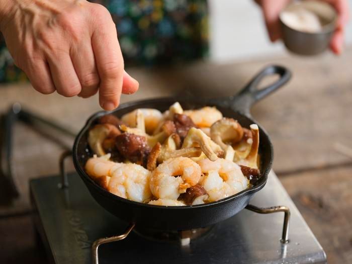 「春シイタケとエビのアヒージョ」に塩を加える様子