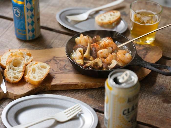 「春シイタケとエビのアヒージョ」とビールがテーブルに並んでいる