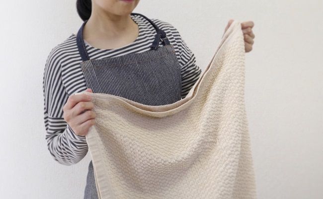 バスタオルを持つエプロン姿の女性