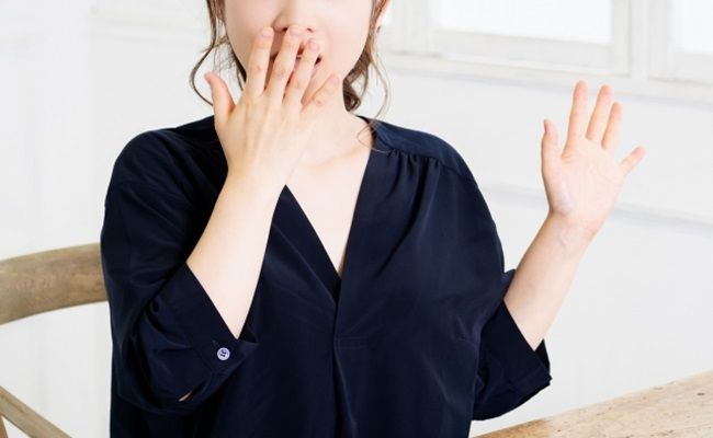 口に手を当てて驚いている女性