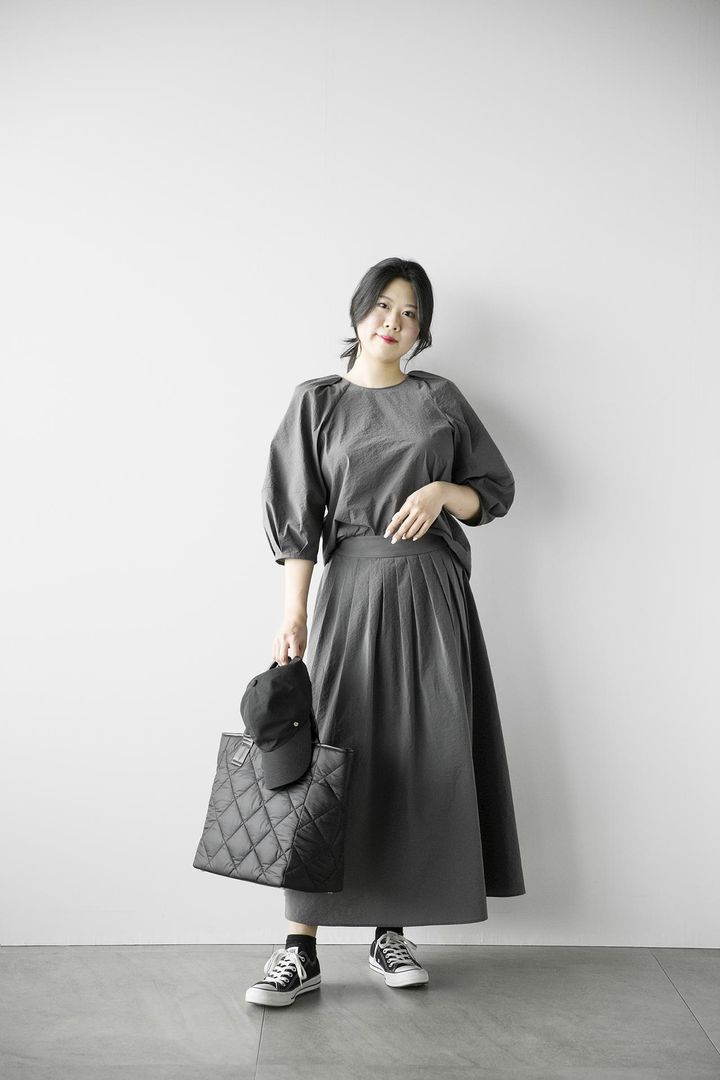 画像: 【プラステ】ハイストレッチナイロンランタンスリーブブラウス（マシンウォッシャブル/接触冷感/はっ水）¥8,990、ハイストレッチナイロンタックフレアスカート（マシンウォッシャブル/接触冷感/はっ水）¥12,000、メタルパーツ付きキャップ ¥5,990、キルティングトートバッグ¥9,990、その他／私物 www.plst.com