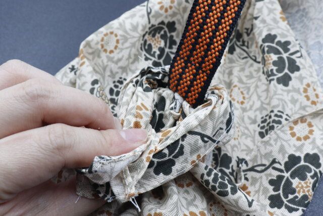 セリアのテープハンドルに通した手ぬぐいを結ぶ様子