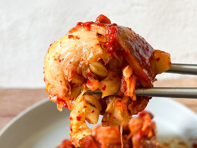 箸で持ち上げた「元祖！おなかいっぱいイカキムチ」