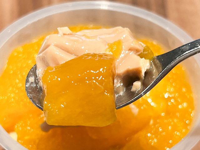 スプーンで持ち上げた「ココナッツクリーム入りスパイシーミルクティーゼリー（マンゴー添え）」