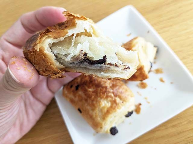 こんがりときつね色に焼きあがった「ミニパンオショコラ生地」を半分に割り、手で持っている様子