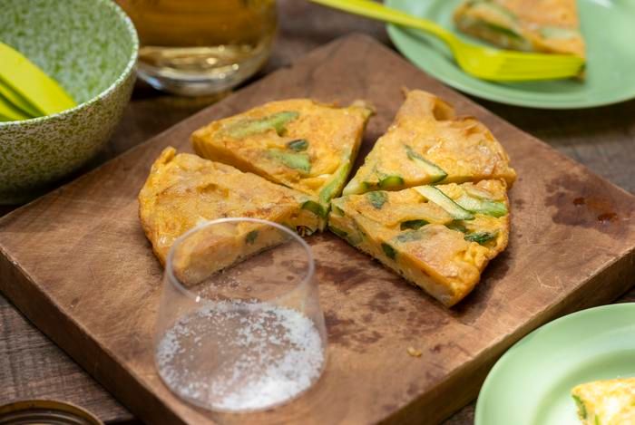 「アスパラとポテトチップスのトルティージャ」とビールがテーブルに並んでいる様子