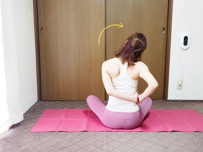 あぐらの姿勢で左手を右肩に添えて、頭を右に倒す