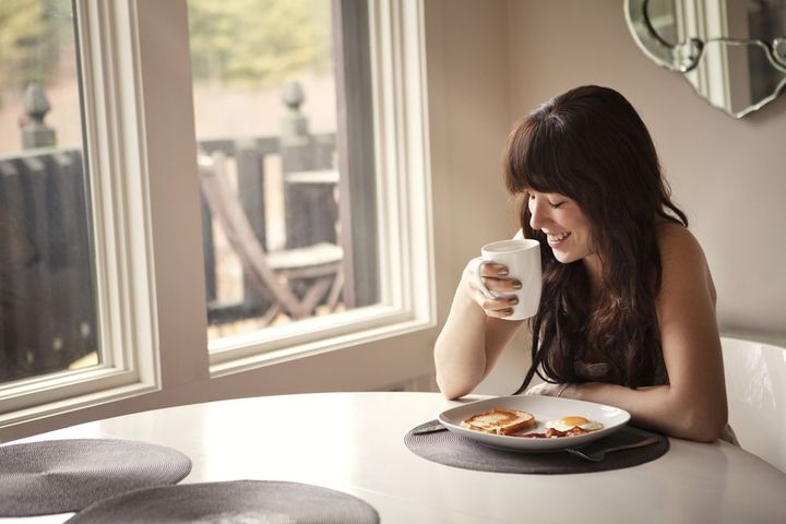 happy woman by breakfast table at home