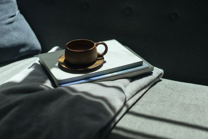 wooden cup of coffee and books on the cozy sofa