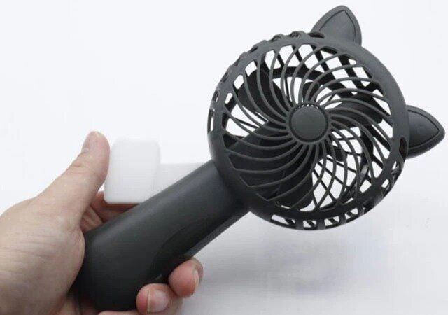 ダイソーのハンディ扇風機（手動ハンドル式、ネコ）のレバーを握る様子