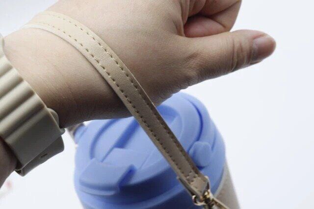 タンブラーにスリーコインズのドリンクカップホルダーを装着し手首に引っ掛けた様子